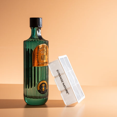 Green bottle with gold label and white ice tray on a beige background