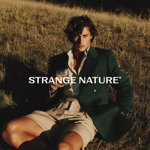 Man in a suit sitting in a field with 'Strange Nature' logo overlay